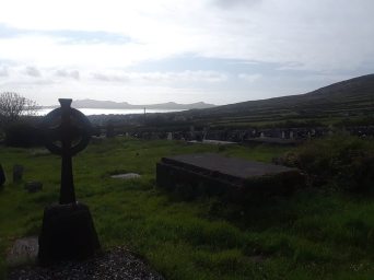 Graveyard at Kilmalkedar Church, with a Celtic cross to the left.